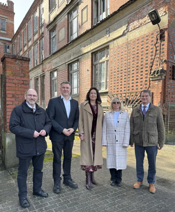 Bild zur Meldung: Bürgermeister Dr. Philipp Wacker, Landrat Ralf Reinhardt, Gesundheitsministerin Britta Müller, KVBB-Vorsitzende Catrin Steininger und Staatssekretär Michael Zaske vor der alten Tuchfabrik.